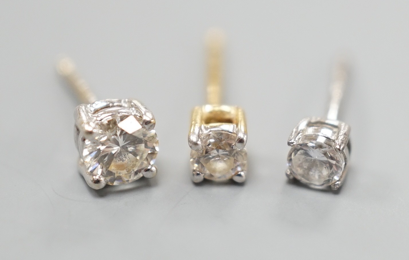 Two odd diamond set ear studs, the stones of various sizes and one paste set ear stud, gross weight 1.3 grams.